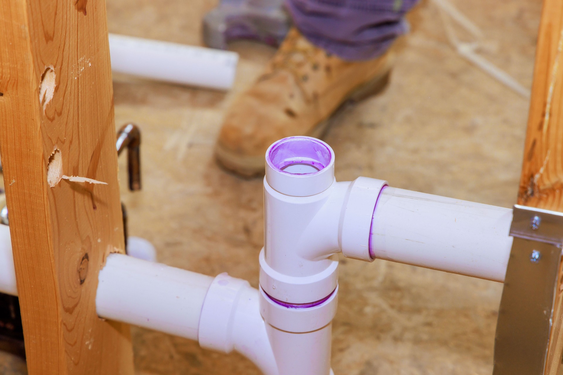 Technician plumber using glue is applied to plastic PVC a pipes